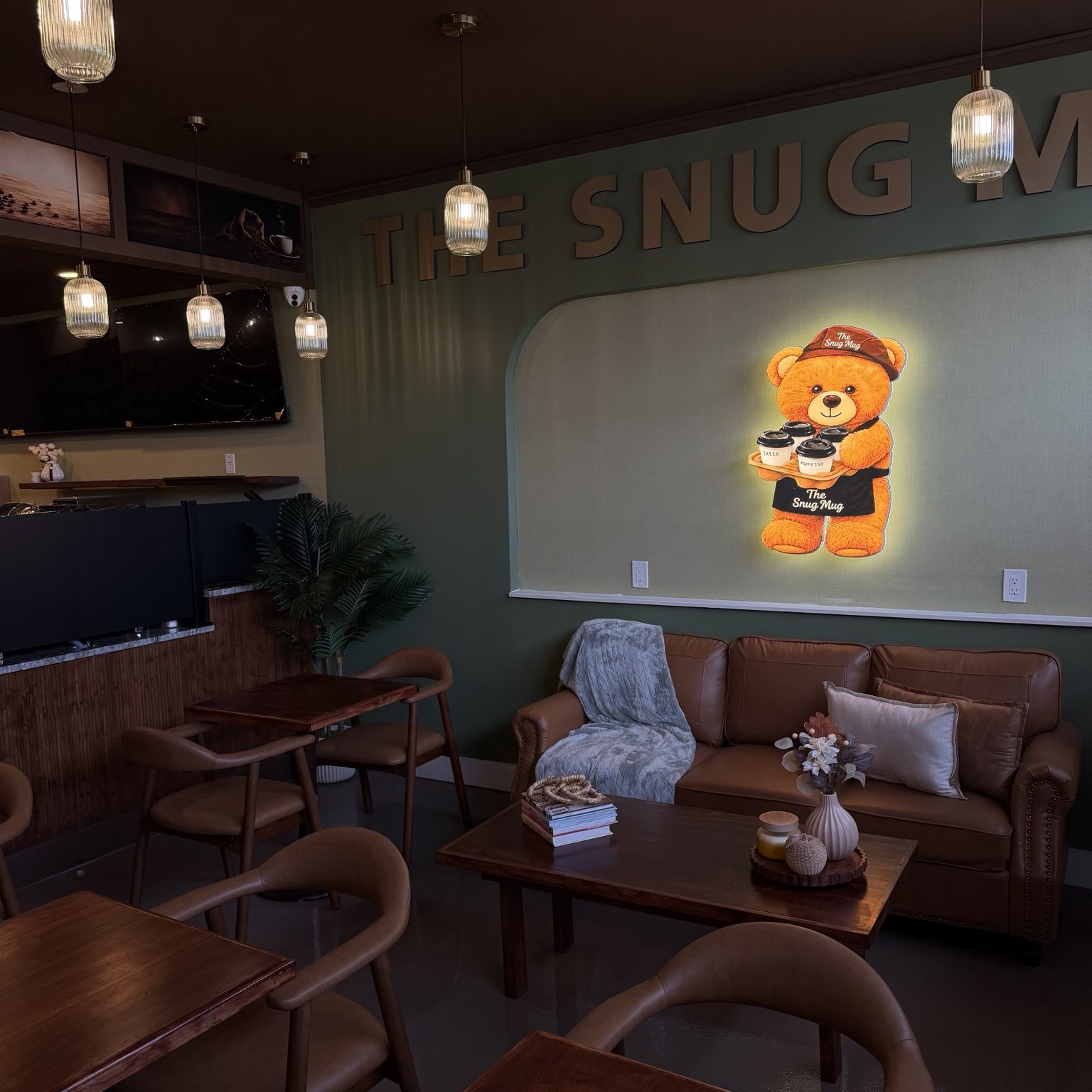 Leather seating and wooden tables under pendant lighting inside The Snug Mug