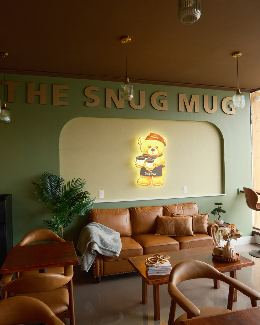 The bear wall inside The Snug Mug: gold letters, the glowing bear sign and the leather sofa